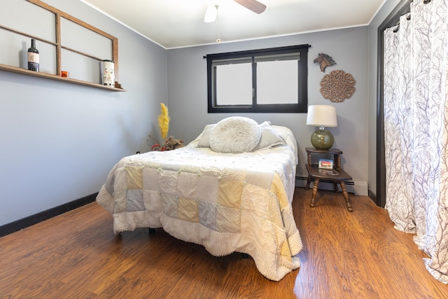 bedroom with baseboards, wood finished floors, crown molding, and a baseboard radiator