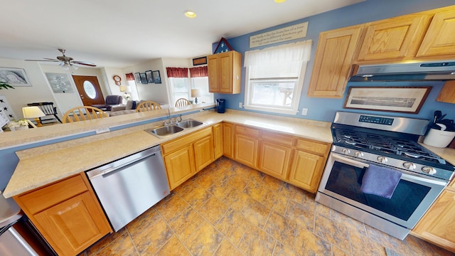 kitchen featuring light countertops, under cabinet range hood, a sink, a peninsula, and appliances with stainless steel finishes