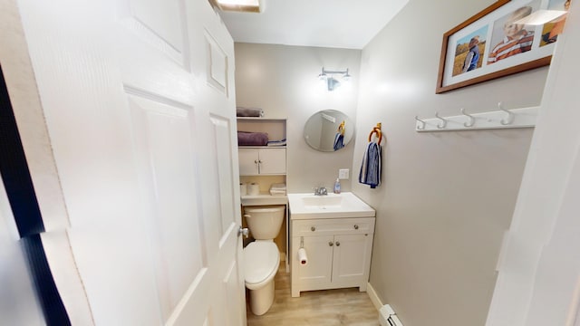 bathroom with toilet, vanity, wood finished floors, a baseboard radiator, and baseboards