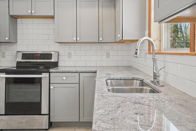 kitchen with a sink, gray cabinets, backsplash, and stainless steel electric stove