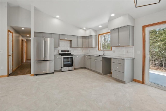 kitchen featuring a sink, gray cabinetry, lofted ceiling, and stainless steel appliances