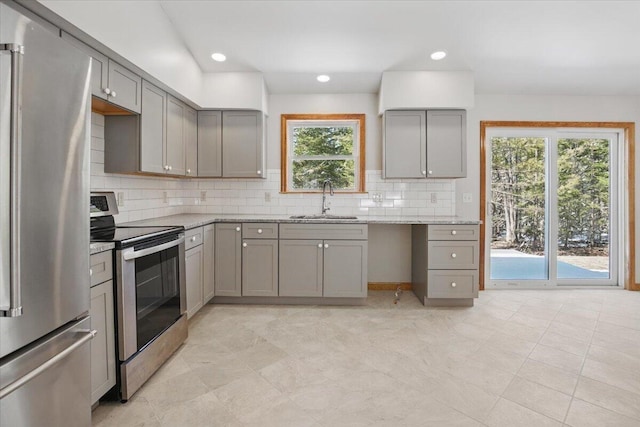 kitchen featuring tasteful backsplash, a sink, stainless steel appliances, gray cabinets, and light stone counters