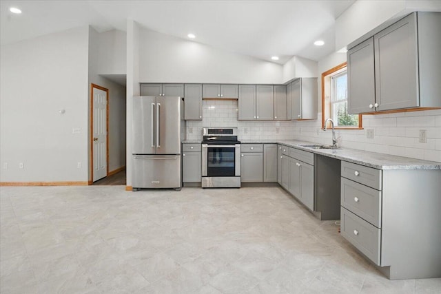 kitchen with a sink, gray cabinetry, vaulted ceiling, and stainless steel appliances