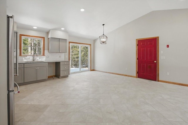 kitchen with vaulted ceiling, a wealth of natural light, gray cabinetry, high end refrigerator, and a sink