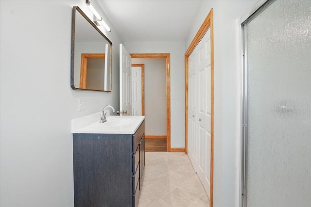 bathroom with a shower stall, vanity, and baseboards