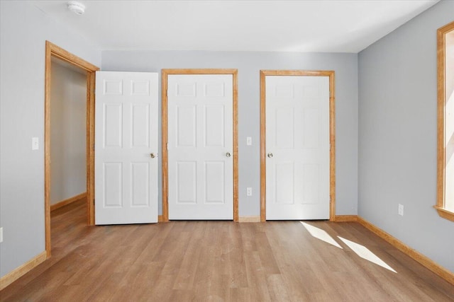 unfurnished bedroom featuring light wood-type flooring and baseboards
