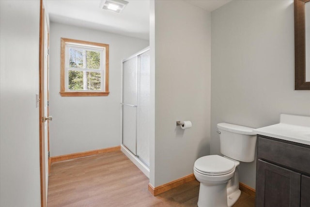 full bathroom with a shower stall, vanity, toilet, wood finished floors, and baseboards