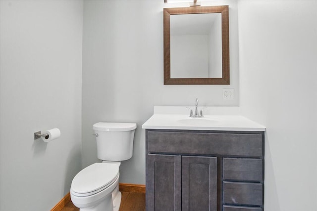 bathroom with toilet, wood finished floors, vanity, and baseboards