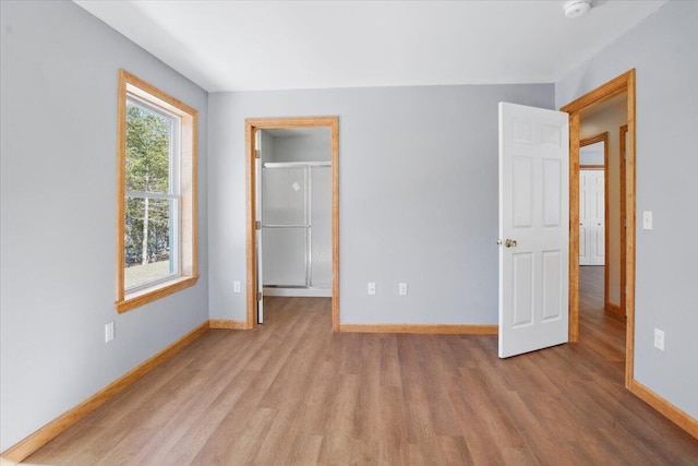 unfurnished bedroom with a spacious closet, baseboards, and wood finished floors