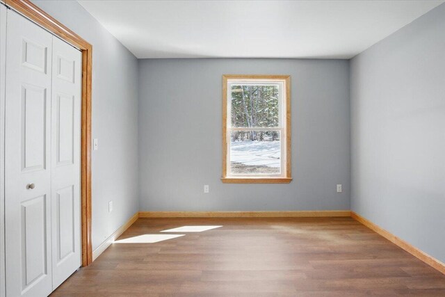 unfurnished bedroom featuring a closet, baseboards, and wood finished floors