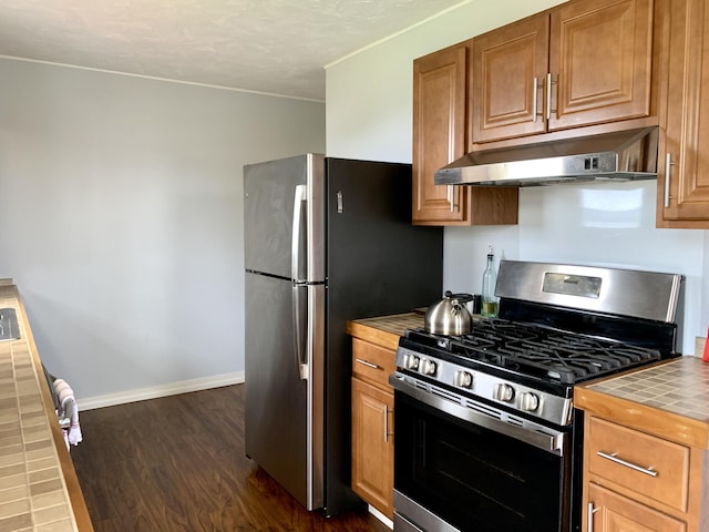 191 Water St, Eastport, ME 04631 - kitchen with appliances with stainless steel finishes, under cabinet range hood, tile countertops, dark wood finished floors, and baseboards