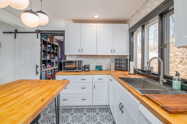 kitchen featuring light tile patterned floors, stainless steel microwave, butcher block countertops, and a sink