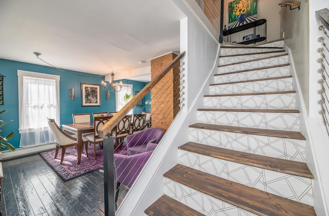 stairs featuring baseboard heating, wood finished floors, and an inviting chandelier