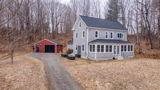 view of front of property featuring an outdoor structure, entry steps, driveway, roof with shingles, and a detached garage