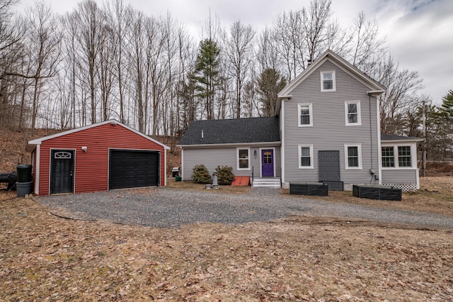 traditional-style house with a garage, a shingled roof, and an outbuilding
