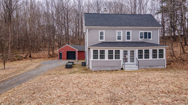 traditional-style home with a garage, entry steps, an outbuilding, and roof with shingles
