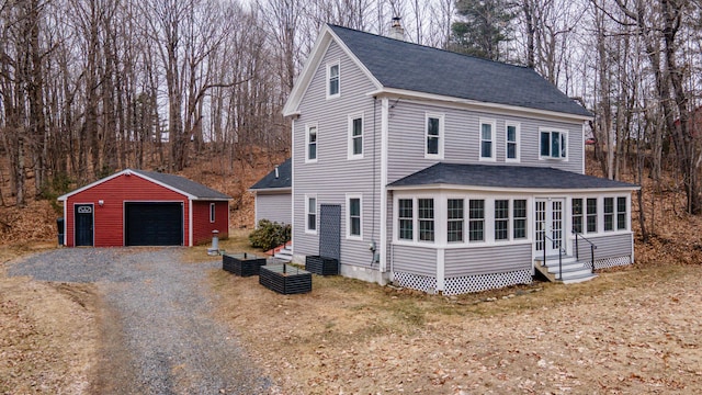 view of front facade with a detached garage, entry steps, a shingled roof, and an outbuilding