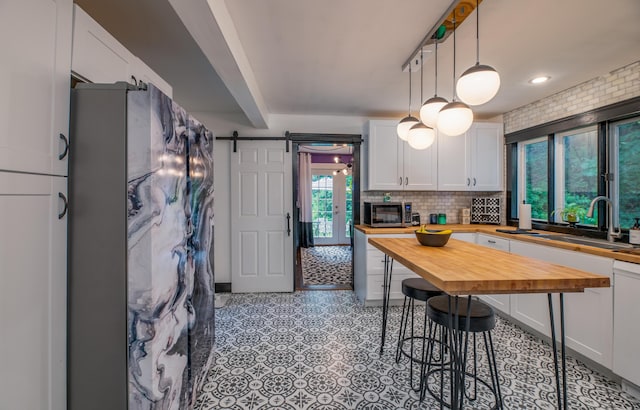 3 Adell Rd, Readfield, ME 04355 - kitchen featuring butcher block counters, a barn door, decorative backsplash, stainless steel microwave, and white cabinets
