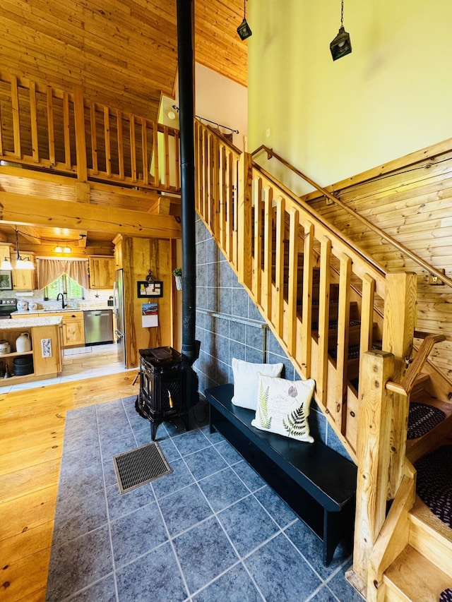 362 N Raymond Rd, Poland, ME 04274 - stairs featuring a wood stove, a high ceiling, wood ceiling, wood finished floors, and wood walls