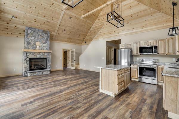 18 Thayer Way, Bethel, ME 04217 - kitchen featuring appliances with stainless steel finishes, a wooden ceiling with exposed beams, high vaulted ceiling, open floor plan, and a fireplace