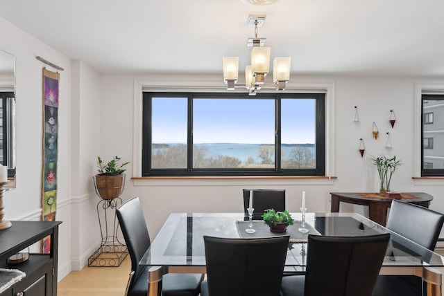 dining space featuring light wood-type flooring, plenty of natural light, and a notable chandelier
