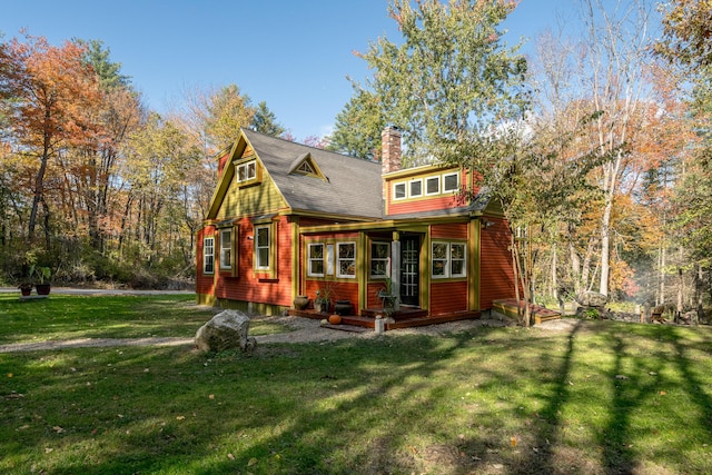 rear view of house with a chimney, a yard, and a shingled roof