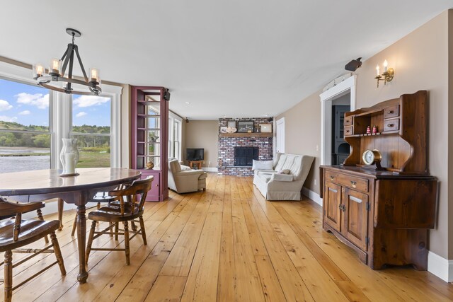 15 Church Ln, Phippsburg, ME 04562 - dining area featuring a chandelier, light wood-type flooring, a fireplace, and baseboards