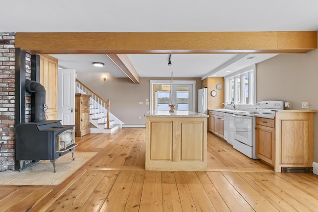 15 Church Ln, Phippsburg, ME 04562 - kitchen with white appliances, a wood stove, a kitchen island, light wood-type flooring, and beam ceiling