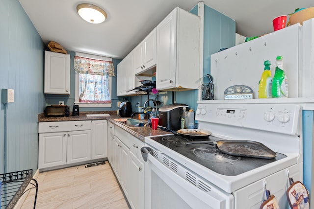 124 Brackett St, Westbrook, ME 04092 - kitchen with dark countertops, fridge, white range with electric stovetop, white cabinets, and a sink