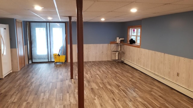 450 W Rd, Waterboro, ME 04087 - basement featuring a baseboard radiator, freestanding refrigerator, a wainscoted wall, a drop ceiling, and wood finished floors