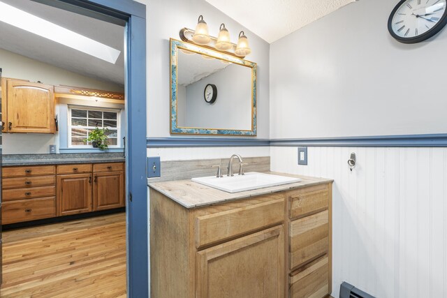450 W Rd, Waterboro, ME 04087 - bathroom featuring vaulted ceiling, a skylight, vanity, wood finished floors, and a wainscoted wall