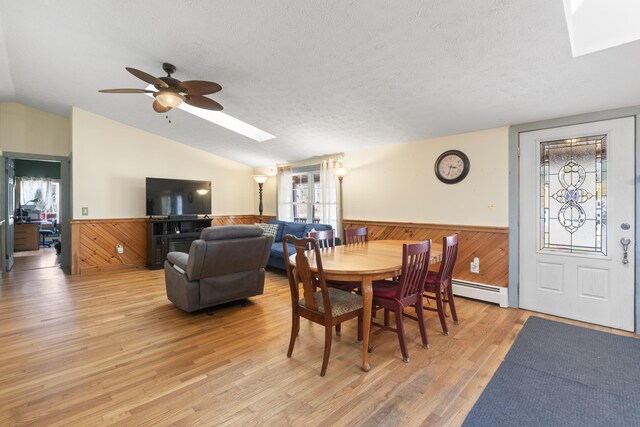 450 W Rd, Waterboro, ME 04087 - dining space featuring a skylight, a wainscoted wall, vaulted ceiling, light wood-style flooring, and a baseboard radiator