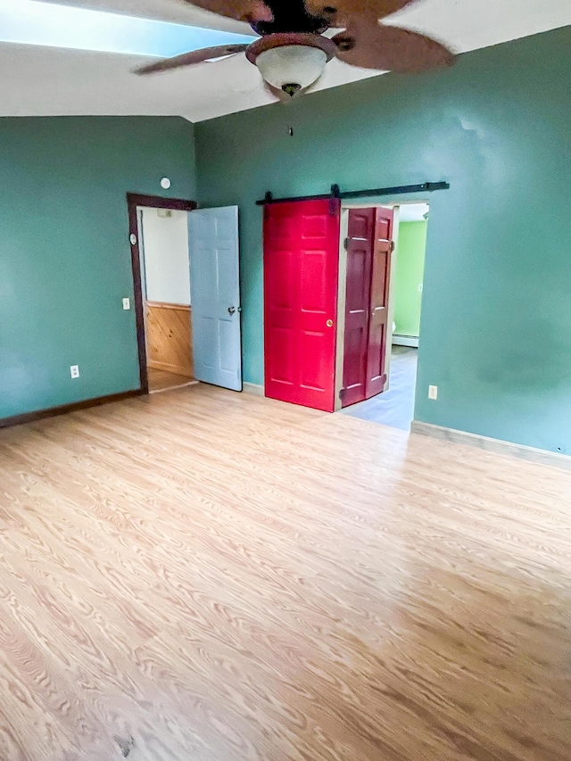 450 W Rd, Waterboro, ME 04087 - unfurnished bedroom featuring a barn door, lofted ceiling, wood finished floors, baseboards, and ceiling fan