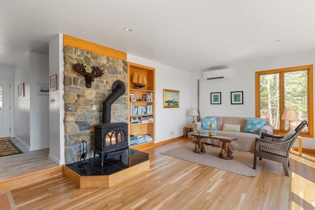 15 Eds Rd, Camden, ME 04843 - living room with a wall mounted air conditioner, a wood stove, wood finished floors, and built in shelves