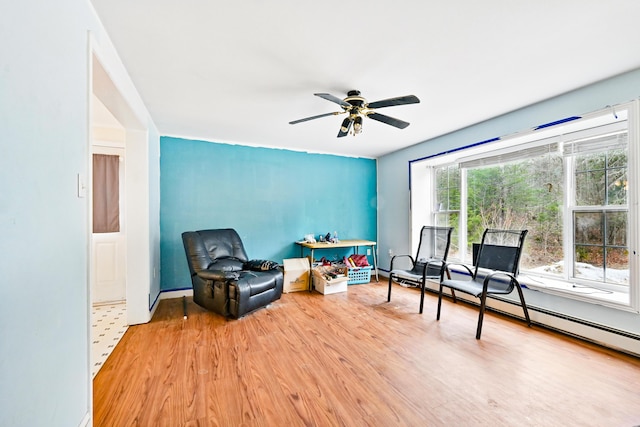 sitting room with baseboard heating, wood finished floors, and a ceiling fan