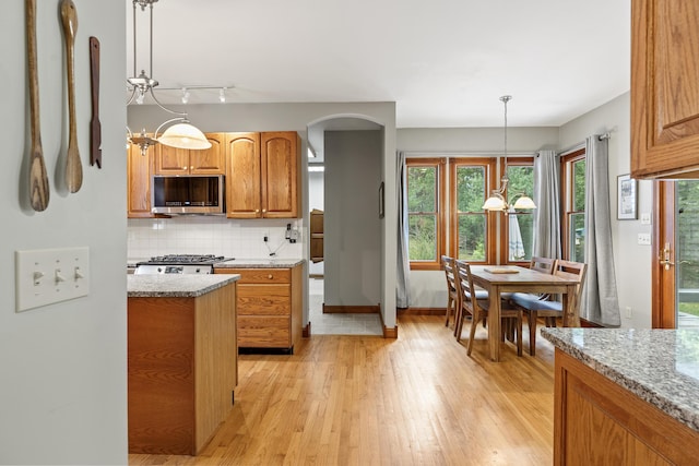 39 Catlin Shore Rd, Harpswell, ME 04079 - kitchen featuring stainless steel microwave, a chandelier, light wood-style flooring, arched walkways, and backsplash