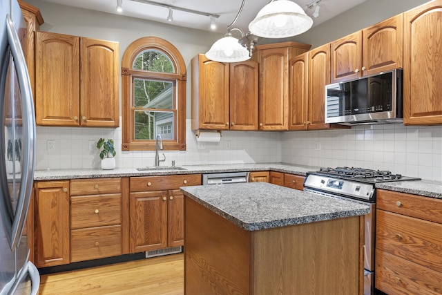 39 Catlin Shore Rd, Harpswell, ME 04079 - kitchen featuring appliances with stainless steel finishes, a sink, rail lighting, decorative backsplash, and light wood-style floors