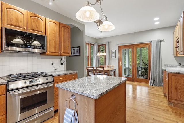 39 Catlin Shore Rd, Harpswell, ME 04079 - kitchen featuring appliances with stainless steel finishes, a center island, decorative backsplash, light wood-style flooring, and light stone counters