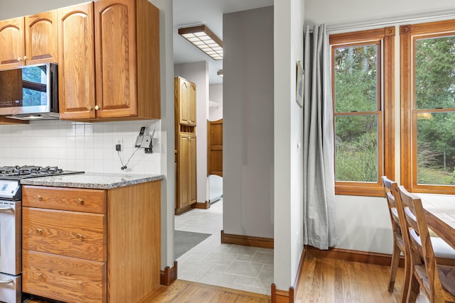 39 Catlin Shore Rd, Harpswell, ME 04079 - kitchen with appliances with stainless steel finishes, decorative backsplash, light stone countertops, baseboards, and brown cabinetry