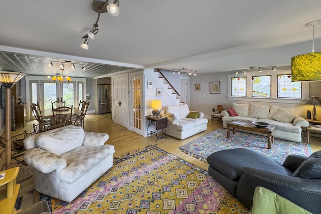 living room featuring stairs, french doors, track lighting, and wood finished floors