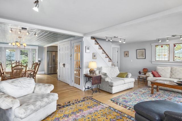 living area with track lighting, french doors, stairs, and wood finished floors