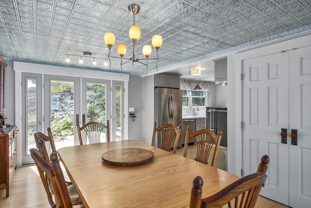 dining area featuring an inviting chandelier, an ornate ceiling, french doors, and light wood-type flooring