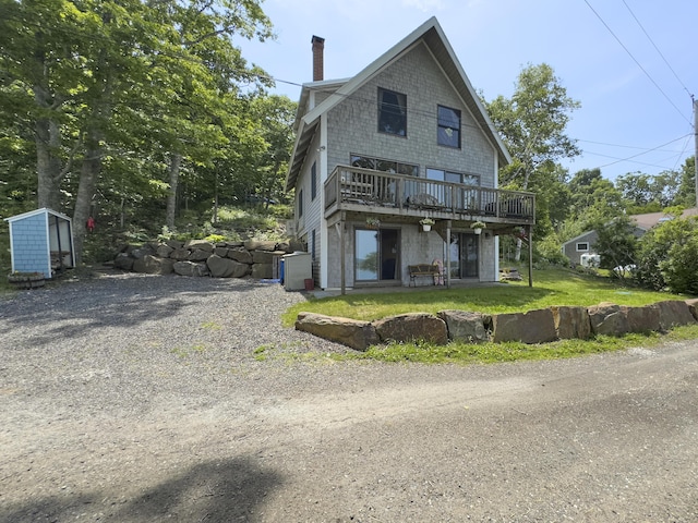 rear view of property with a wooden deck, a chimney, and a yard