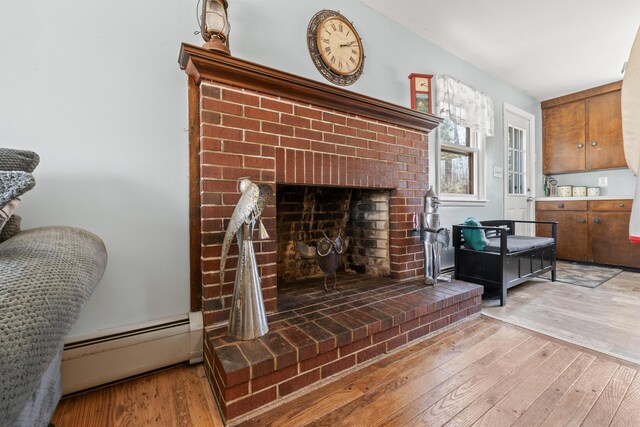 369 Windham Center Rd, Windham, ME 04062 - living room with a brick fireplace, a baseboard radiator, and hardwood / wood-style floors