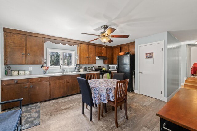 369 Windham Center Rd, Windham, ME 04062 - kitchen with light countertops, under cabinet range hood, a sink, light wood-style floors, and appliances with stainless steel finishes