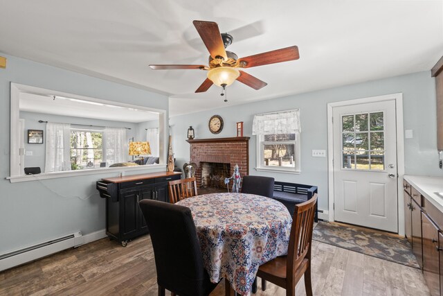 369 Windham Center Rd, Windham, ME 04062 - dining space with a ceiling fan, a brick fireplace, a baseboard heating unit, and wood finished floors