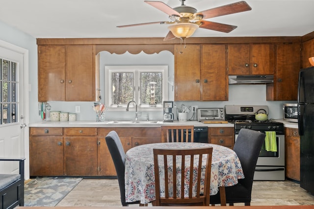 369 Windham Center Rd, Windham, ME 04062 - kitchen with light countertops, appliances with stainless steel finishes, under cabinet range hood, a sink, and light wood-style floors