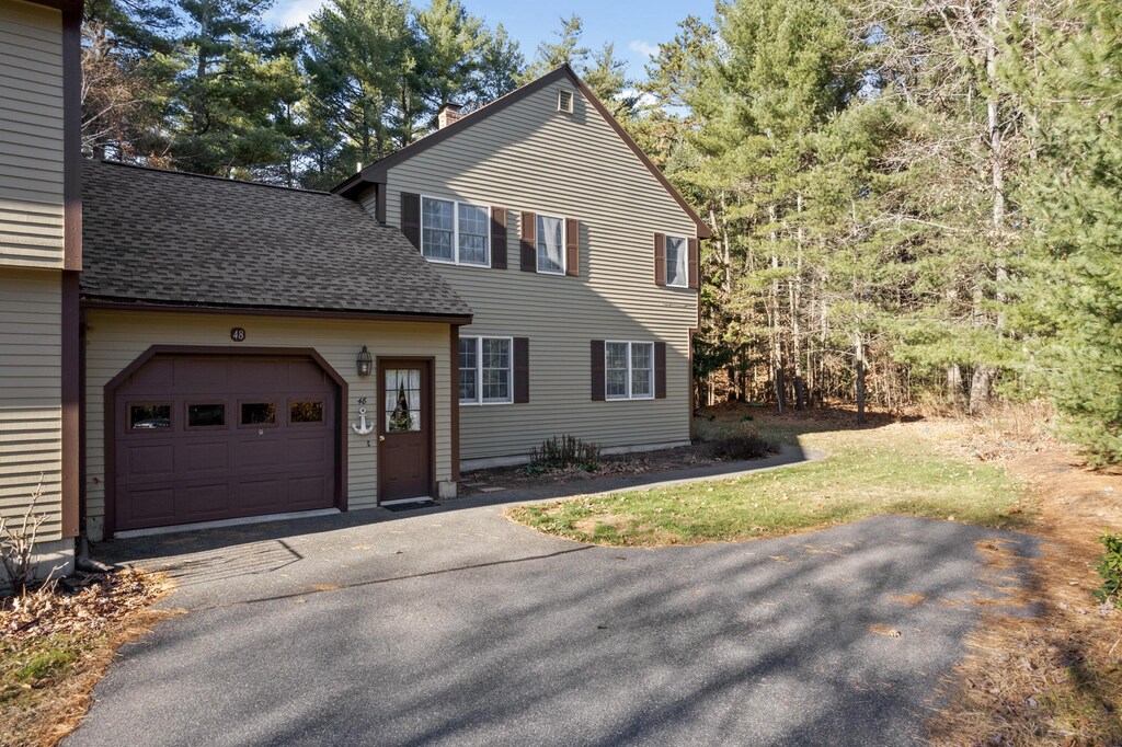 view of front of house with a chimney, a shingled roof, aphalt driveway, and an attached garage