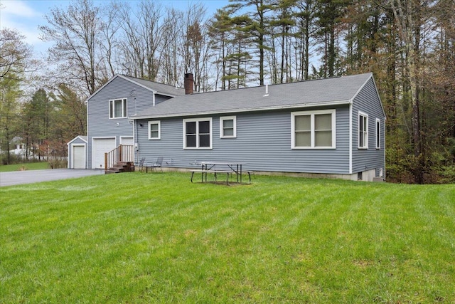 rear view of property featuring a chimney, an attached garage, a yard, and asphalt driveway