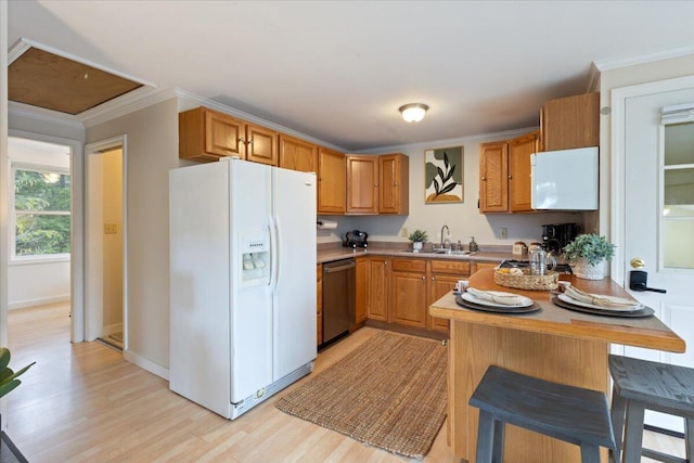 kitchen featuring white appliances, a peninsula, light wood-style floors, a sink, and light countertops